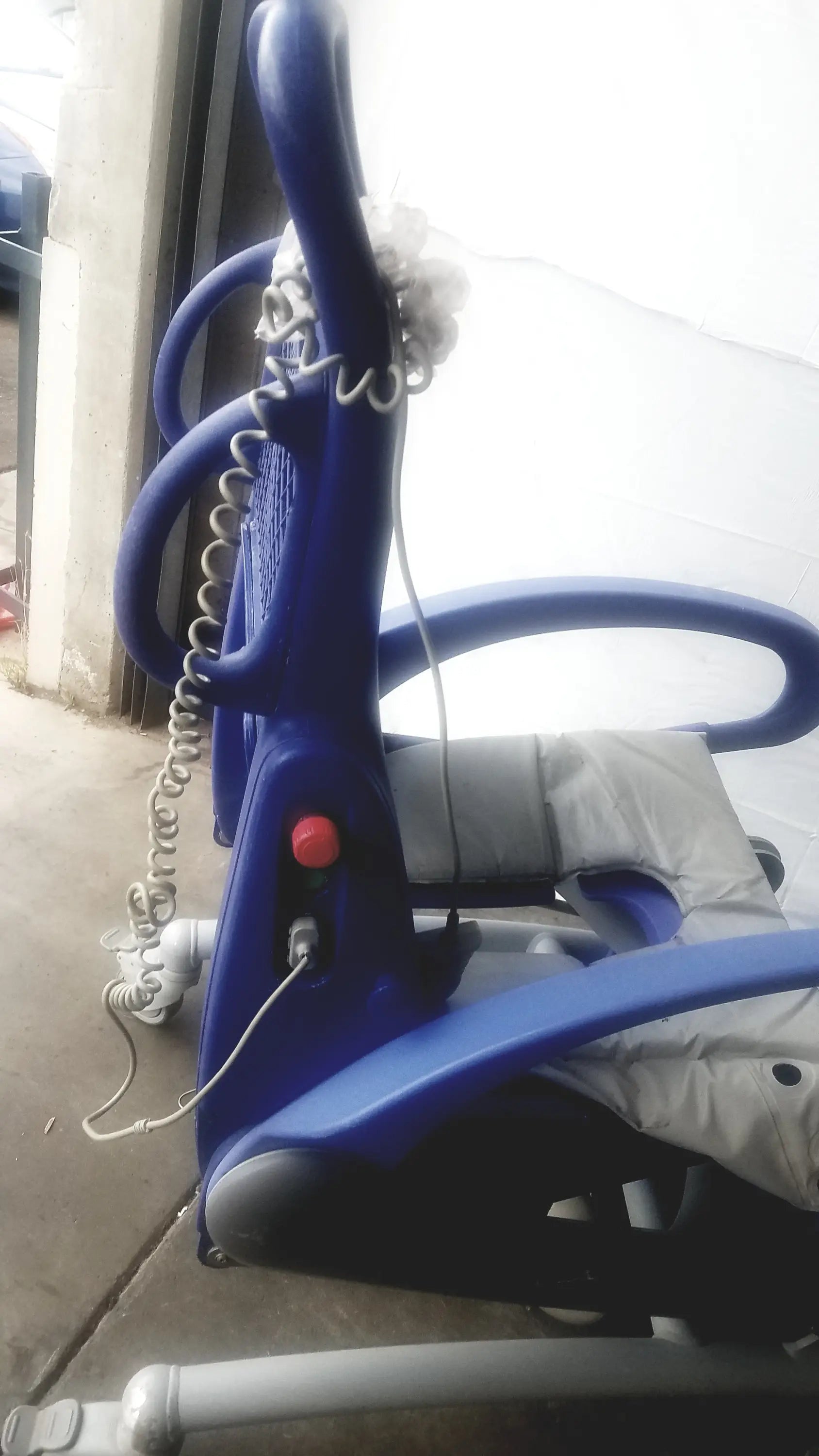 Blue plastic arjo carendo multipurpose hygiene chair with coiled cord and red button for effective multipurpose hygiene