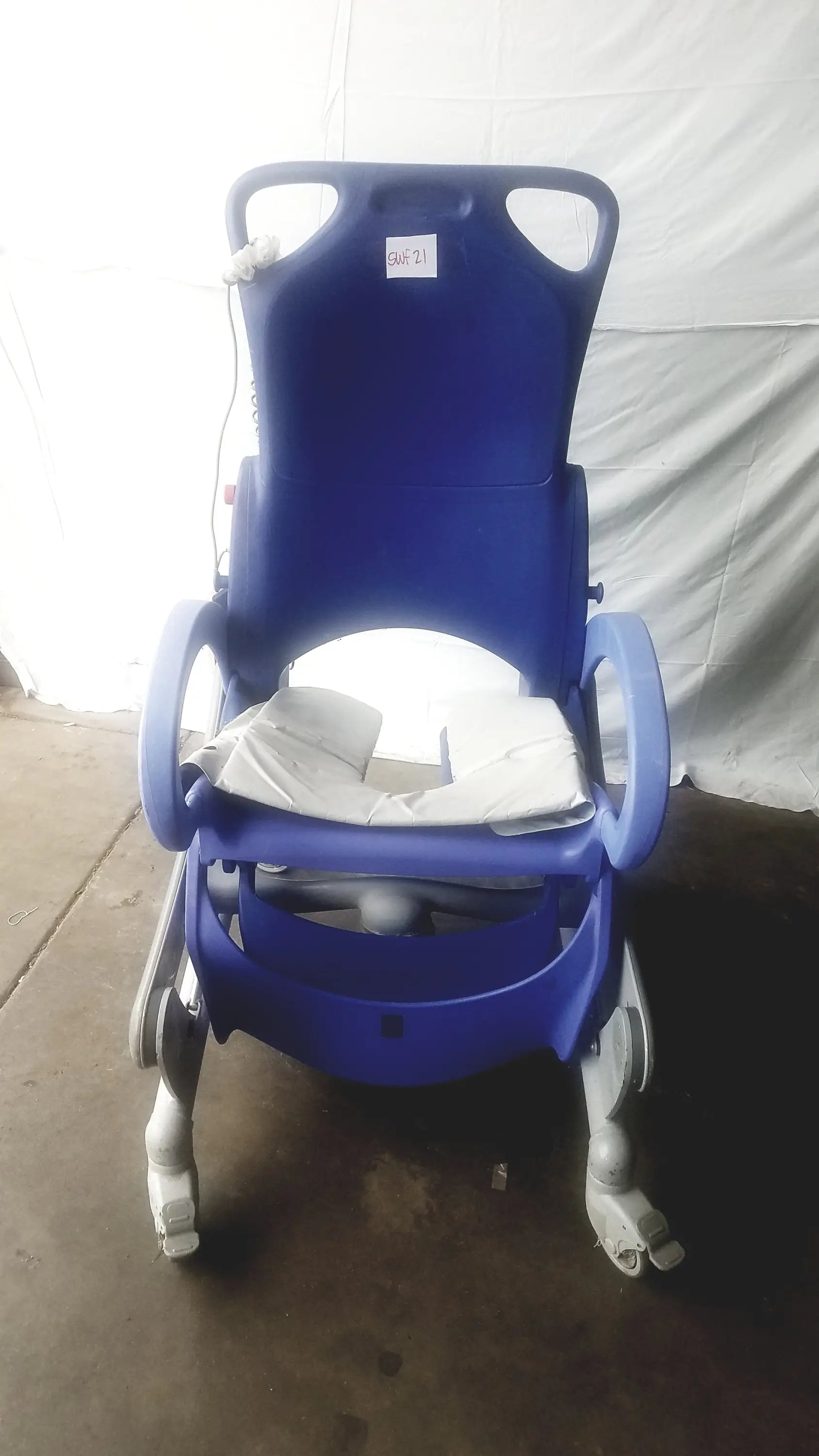 Blue plastic arjo carendo multipurpose hygiene chair with white cushion and gray wheels for hospital use