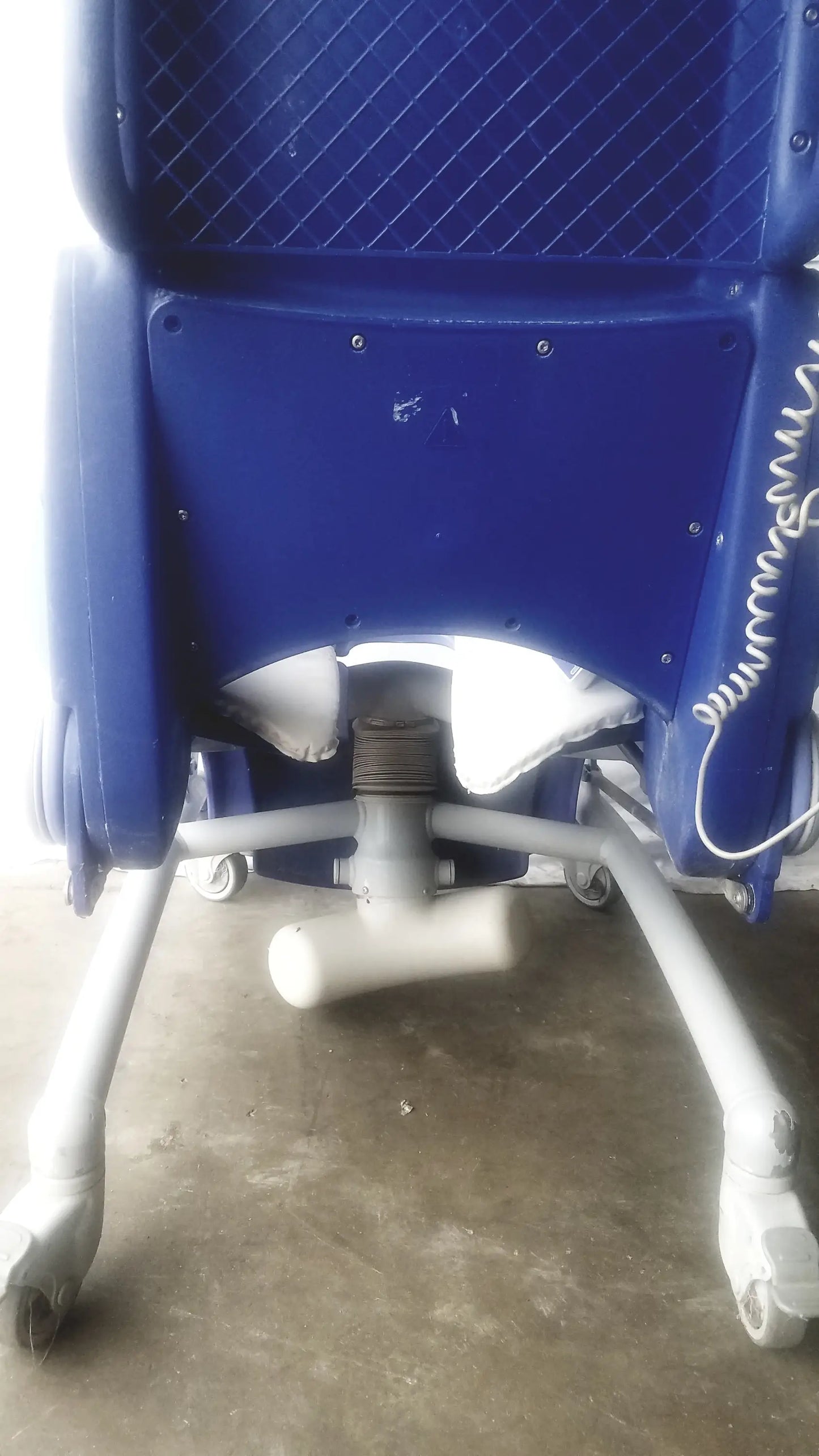 Blue plastic arjo carendo multipurpose hygiene chair with white casters and coiled cable on the side for multipurpose hygiene use