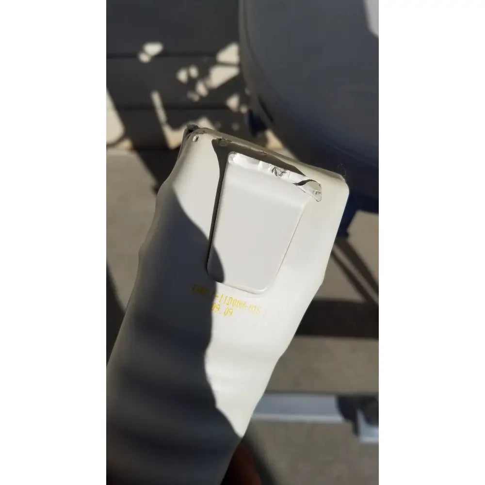 White plastic rectangular flap with yellow text showing wear on the back side of an arjo huntleigh power electric walker