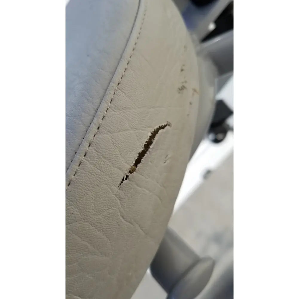 White leather car seat with visible stitching and tear on the arjo huntleigh power electric walker lift ambulatory support