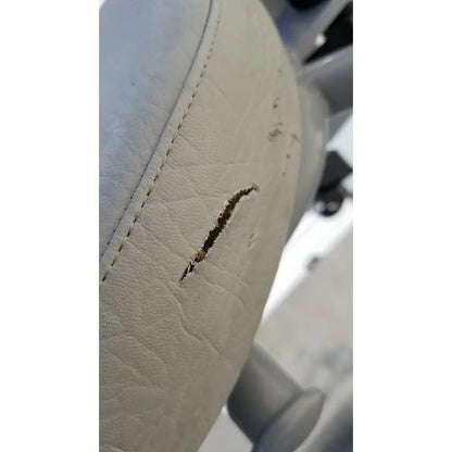 White leather car seat with visible stitching and tear on the arjo huntleigh power electric walker lift ambulatory support