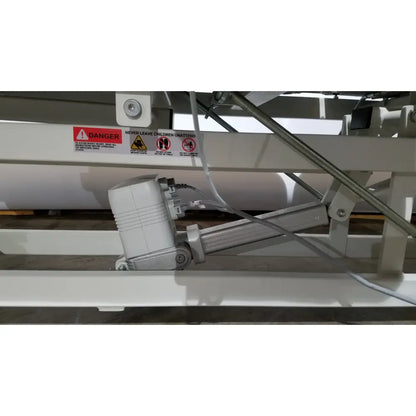 White electric lift mechanism with metallic arm and cables on the back side of armedica am 300 three section treatment table