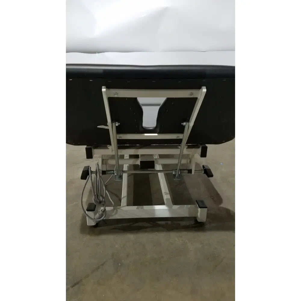 Black Armedica AM-300 three section treatment table with padded surface and silver metal frame with adjustable legs
