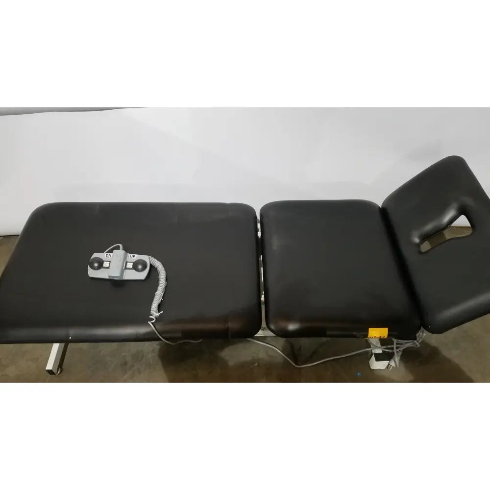 Black armedica am-300 three section treatment table with gray control panel and coiled cord for chiropractic use