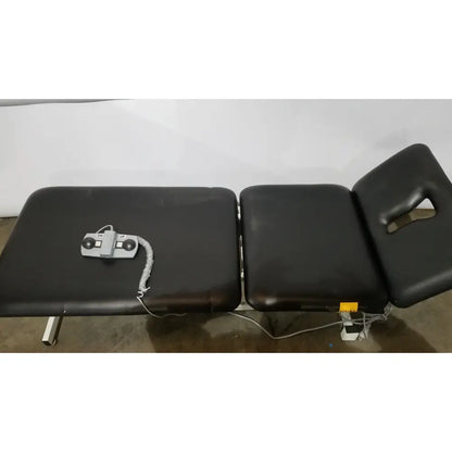 Black armedica am-300 three section treatment table with gray control panel and coiled cord for chiropractic use