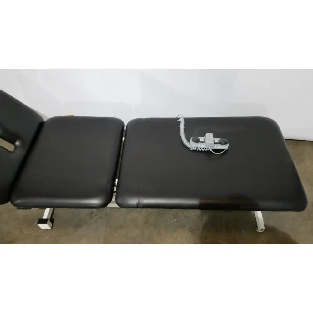 Black padded Armedica AM-300 three section treatment table with gray control unit on surface for chiropractic use