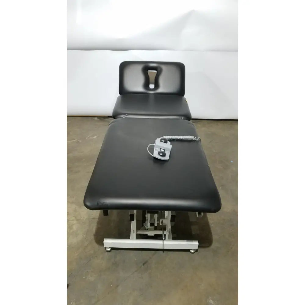 Armedica am-300 black padded three section treatment table with adjustable height and silver control unit on surface
