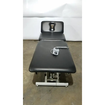Armedica am-300 black padded three section treatment table with adjustable height and silver control unit on surface