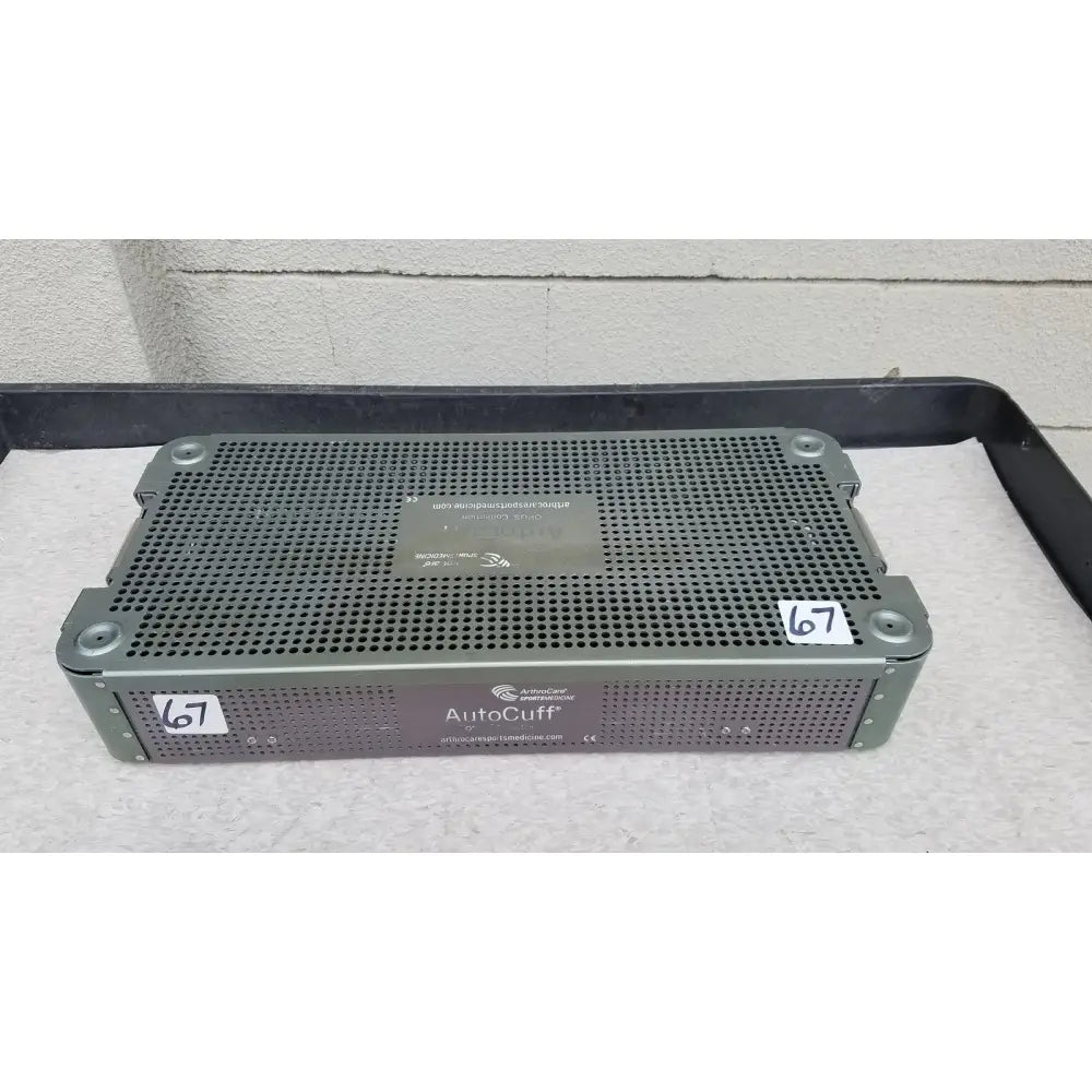 Gray perforated metal medical sterilization tray from arthrocare autocuff opus collection with brand label and website sticker