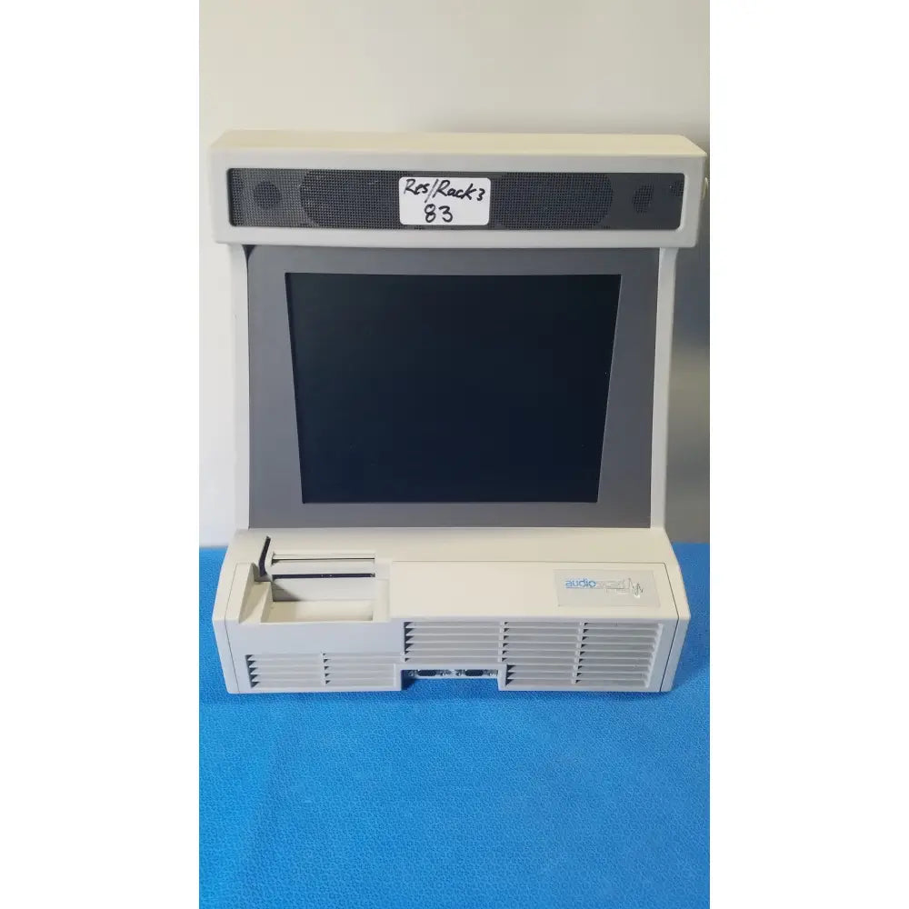 Beige plastic desktop computer with black screen and ventilation grilles front of audioscan verifit vf-1 hearing analyzer