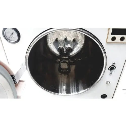 The interior of a white autoclave portable steal sterilizer packing TR250NM-1 with metallic reflective surface and pressure gauge