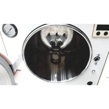The interior of a white autoclave portable steal sterilizer packing TR250NM-1 with metallic reflective surface and pressure gauge