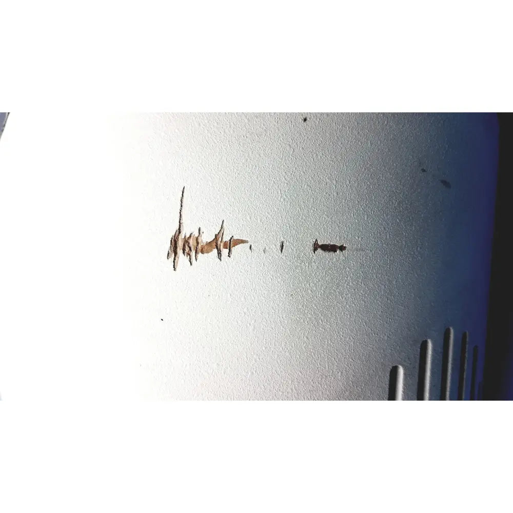 A worn brownish-orange crackling mark on a textured white surface of the automet 2 variable speed grinder-polisher 120v