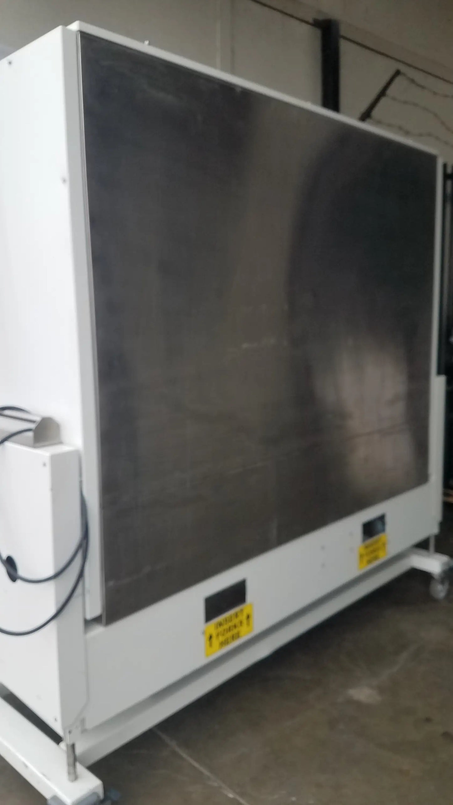 Industrial-grade white metal Baker SS-600 sterilshield positive pressure isolator with dark gray panel and yellow warning labels