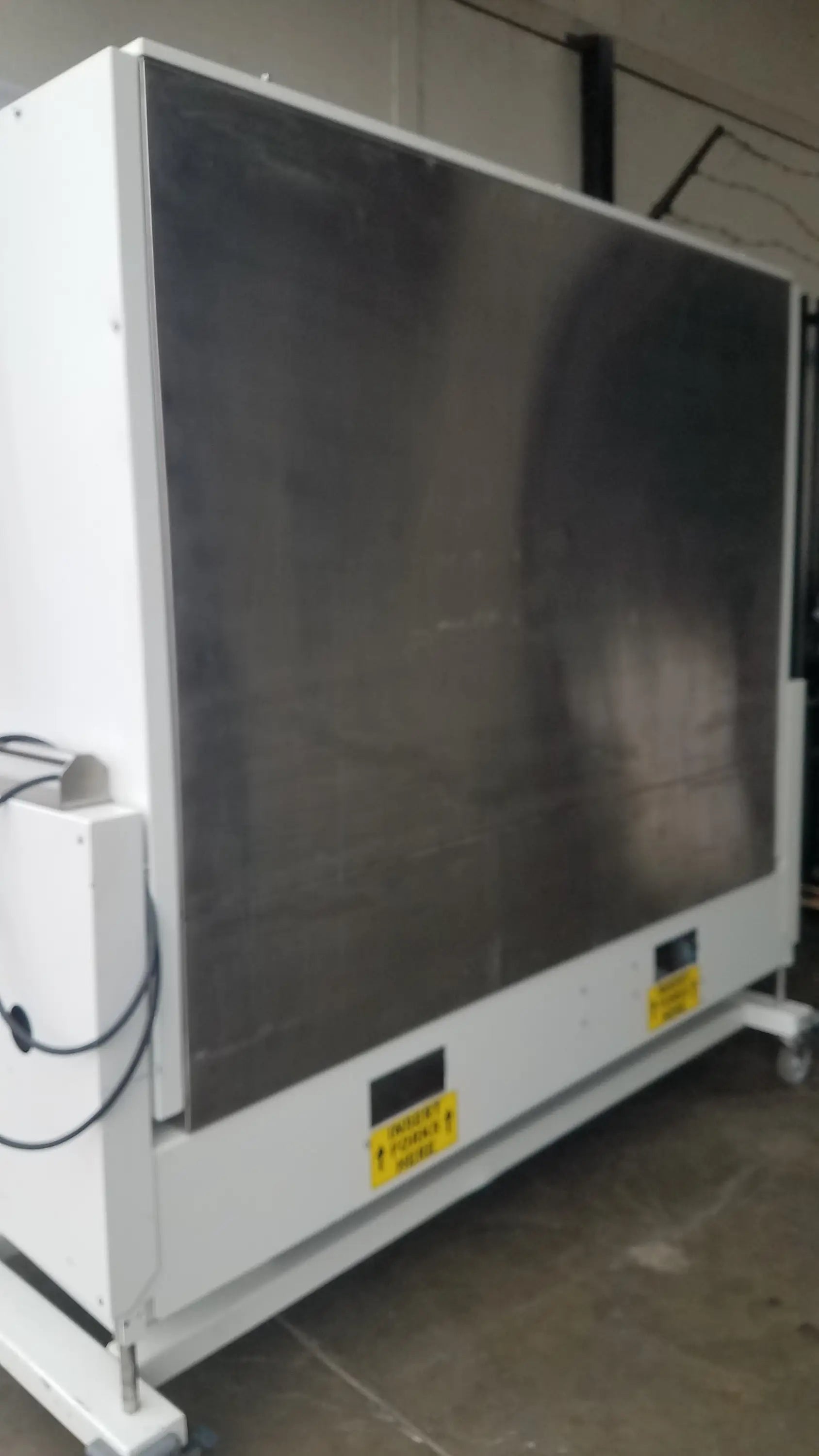 Industrial-grade white metal Baker SS-600 sterilshield positive pressure isolator with dark gray panel and yellow warning labels