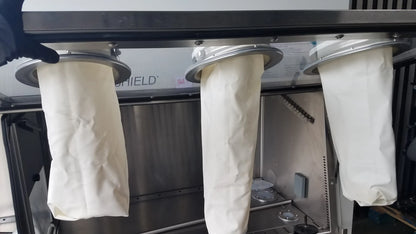 Three white cylindrical filter bags with metallic rims hang on baker ss-600 sterilshield positive pressure isolator