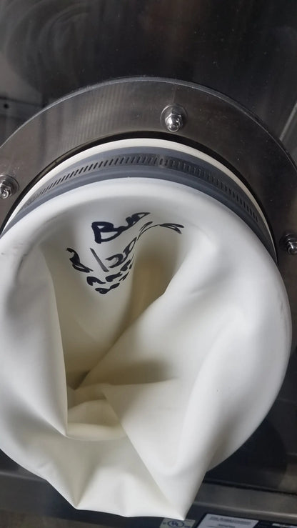 White fabric filter bag with black markings secured by metallic flange and gasket on baker ss-600 sterilshield positive pressure isolator