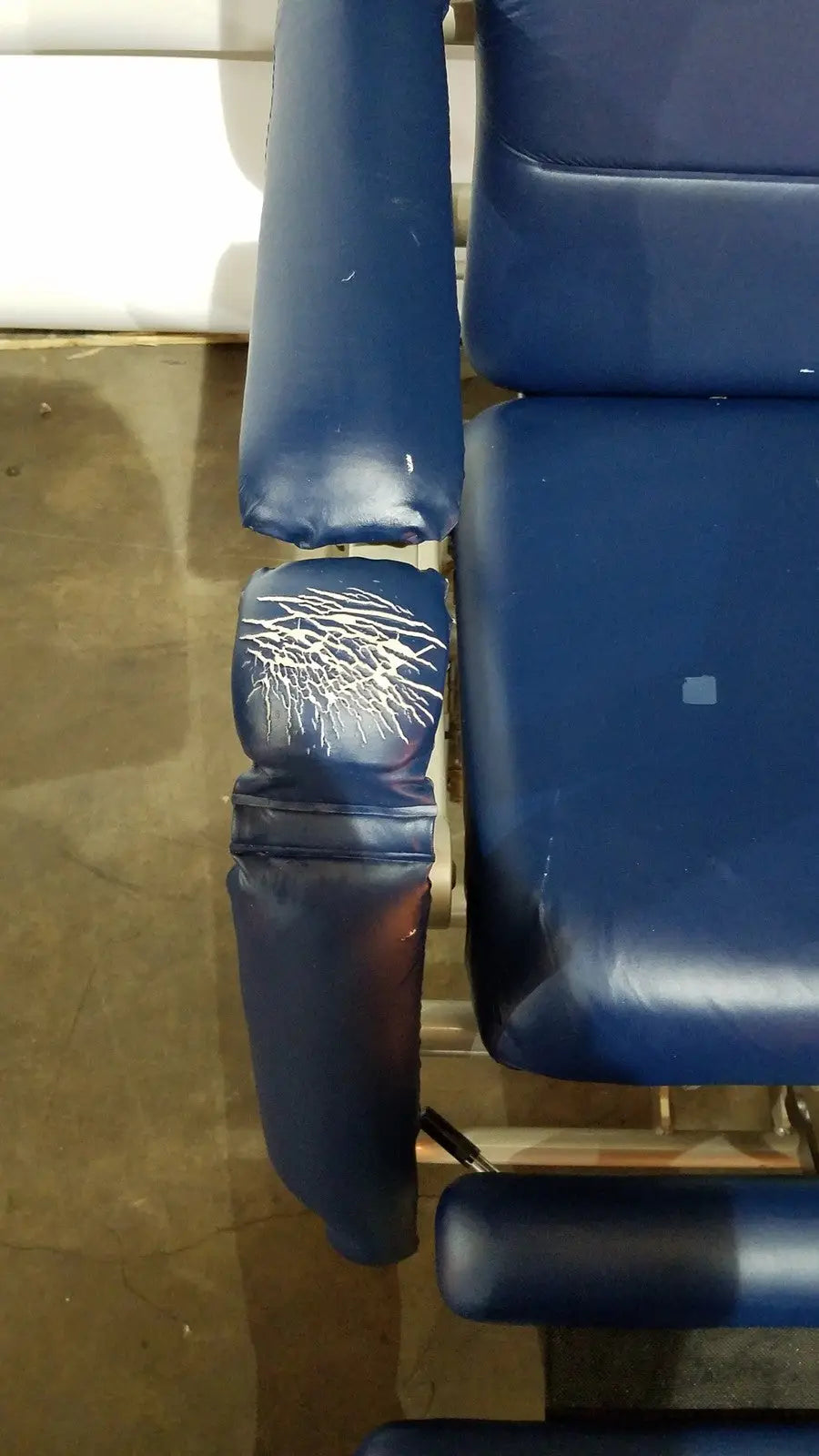 Blue padded armrest with visible wear on barton convertible medical chair designed for treatment use
