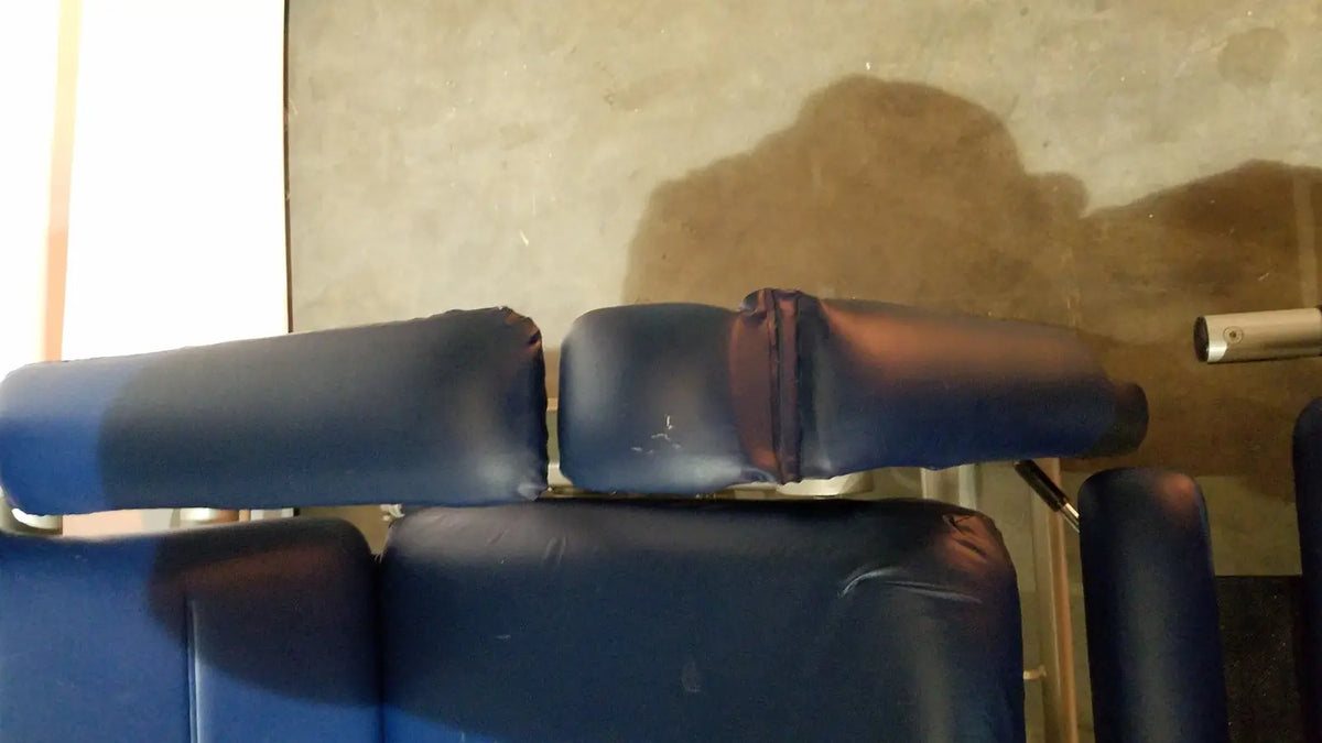 Blue padded headrest with worn dark vinyl finish on barton convertible medical chair back side