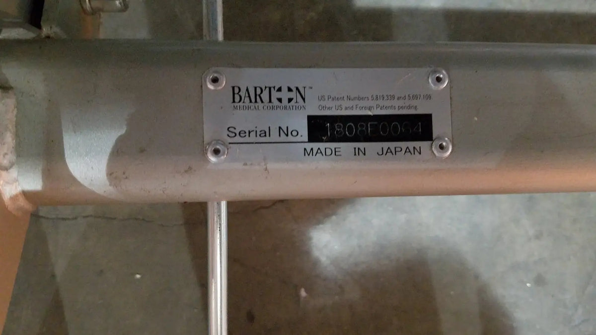 Silver metallic cylindrical tube with barton medical corporation label on the barton convertible medical chair
