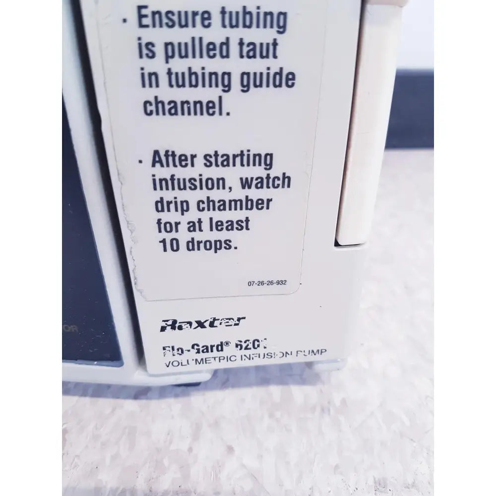 White plastic baxter 2m8063 flo-gard 6201 volumetric infusiion pump with black printed instructions and model labeling