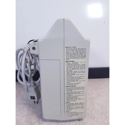 White plastic baxter 2m8063 volumetric infusion pump with printed instructions and labels for medical use