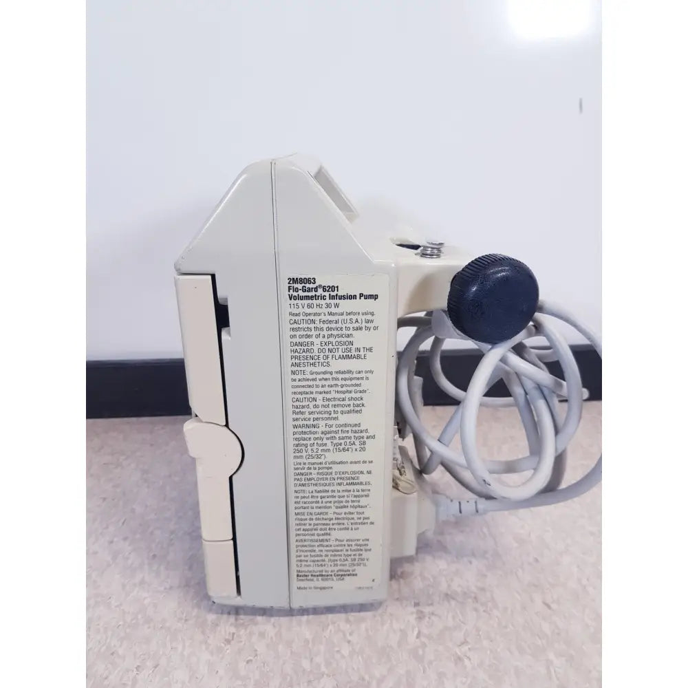 White plastic baxter 2m8063 flo-gard 6201 volumetric infusiion pump with blue knob and coiled tubing shown as-is
