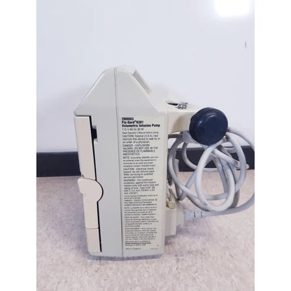 White plastic baxter 2m8063 flo-gard 6201 volumetric infusiion pump with blue knob and coiled tubing shown as-is