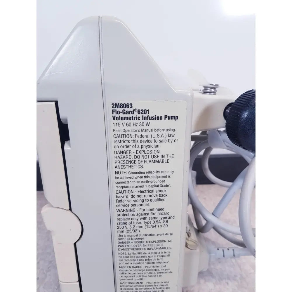 White plastic baxter 2m8063 volumetric infusiion pump with black knob and labeled side panel specifications back view
