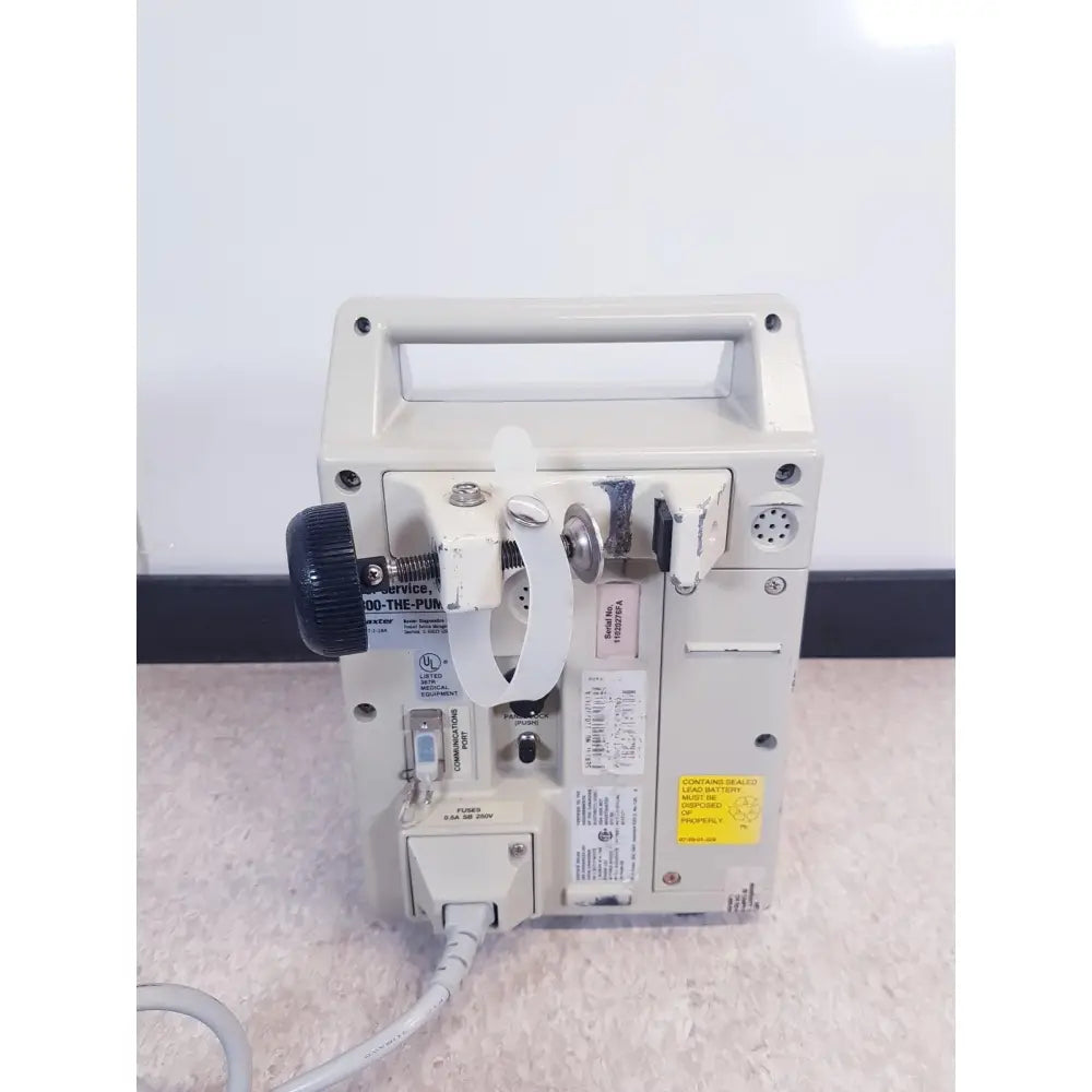 Beige baxter 2m8063 volumetric infusion pump with black knob and white clamps for precise medical fluid control