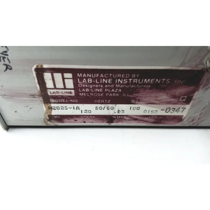 A weathered brown metal label with white text from baxter scientific products h2025-1a multi-blok heater