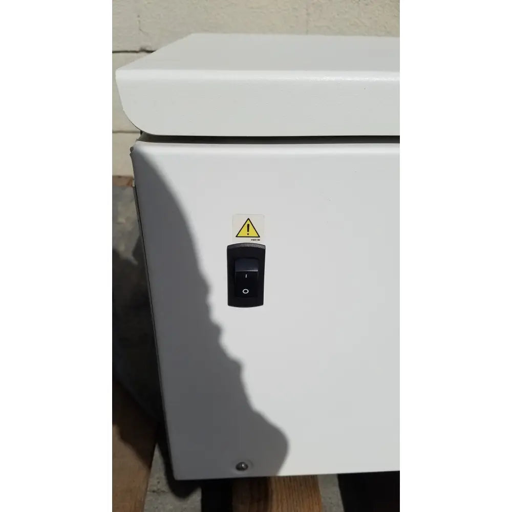White industrial electrical enclosure with black toggle switch and yellow warning label on beckman coulter avanti J-15R centrifuge