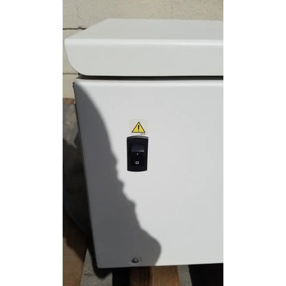 White industrial electrical enclosure with black toggle switch and yellow warning label on beckman coulter avanti J-15R centrifuge