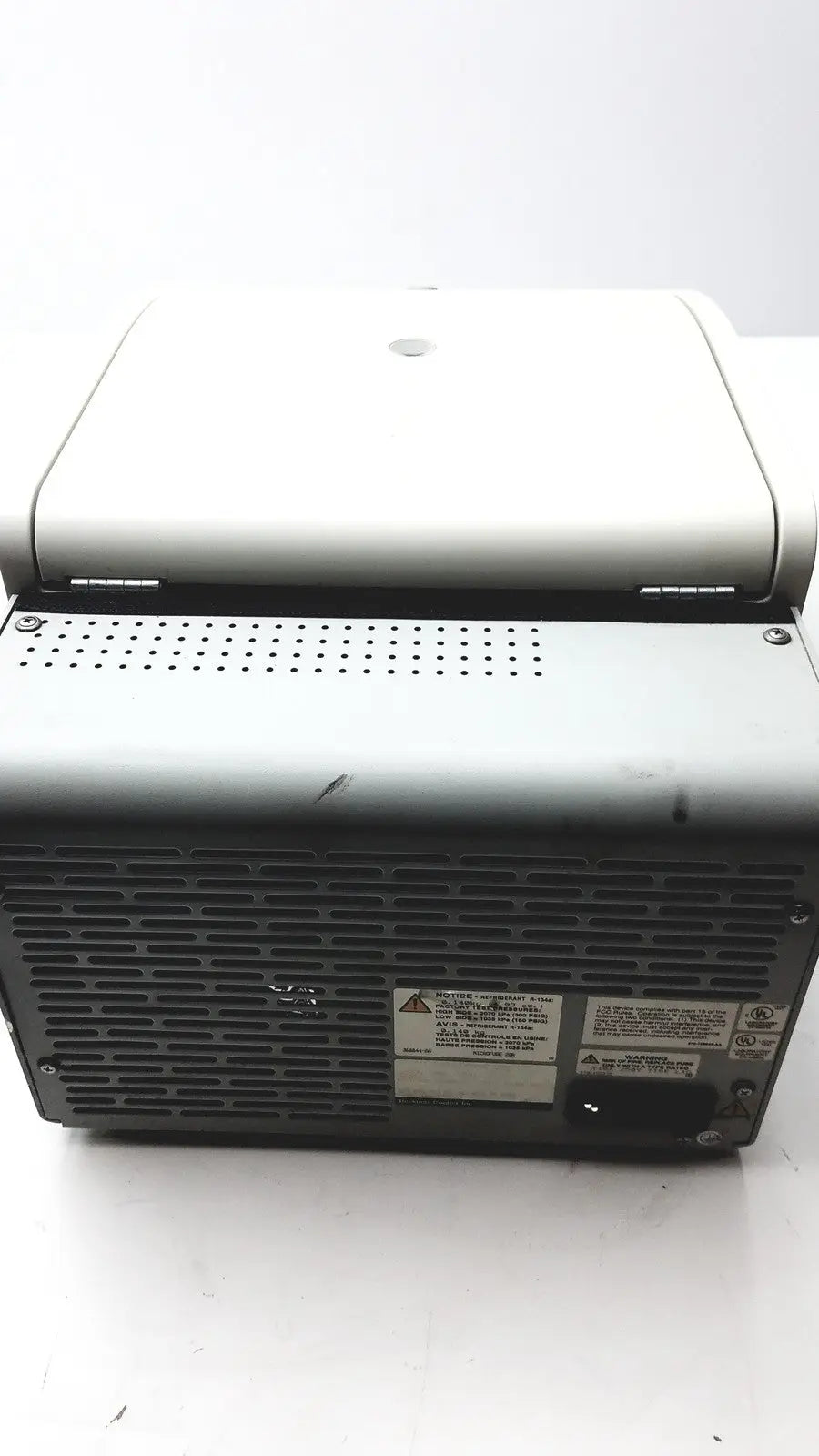 Back side of gray and white beckman coulter microfuge 22r centrifuge with perforated vented panel and warning labels
