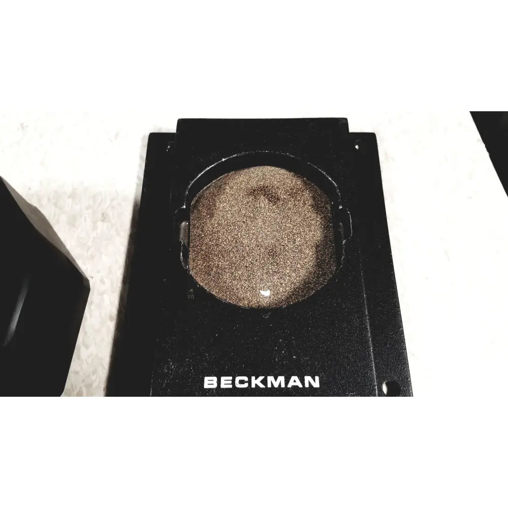 Black beckman coulter ultracentrifuge circular sample holder containing brown granular substance for coulter ultracentrifuge unit
