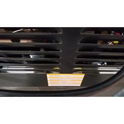 Black plastic grille with horizontal slats and yellow warning label on the back of beckman j2-21 refrigerated centriifuge