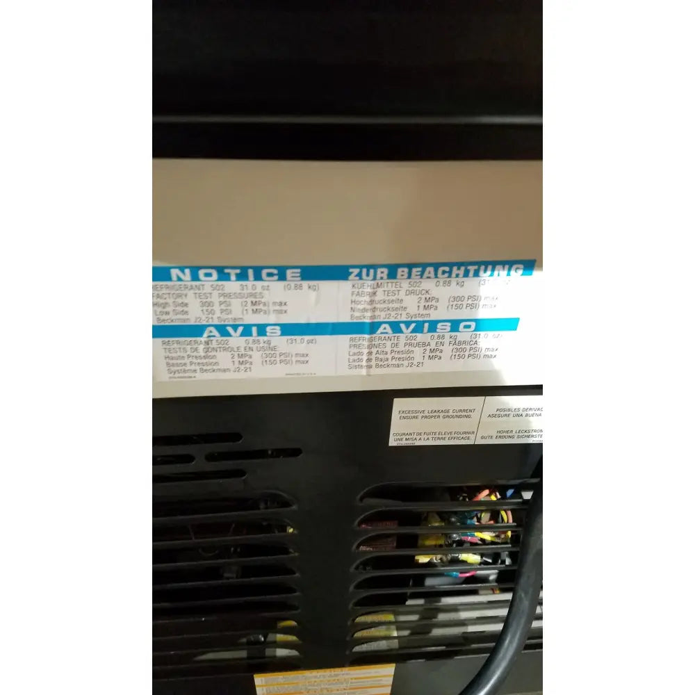 Black industrial air conditioning unit with white label showing specs on the back of a beckman j2-21 refrigerated centriifuge
