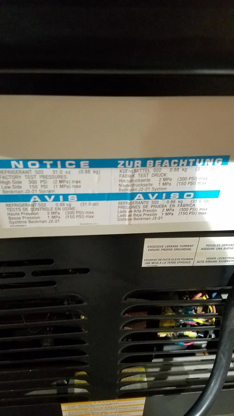 Black industrial air conditioning unit with white label showing specs on the back of a beckman j2-21 refrigerated centriifuge