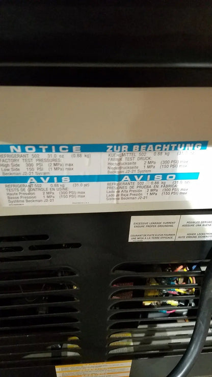 Black industrial air conditioning unit with white label showing specs on the back of a beckman j2-21 refrigerated centriifuge
