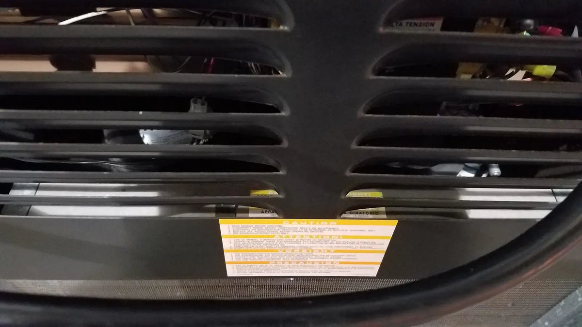 Black plastic grille with horizontal slats and yellow warning label on the back of beckman j2-21 refrigerated centriifuge