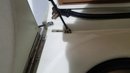 Black power cord with metallic plug attached to the back of a beckman j2-21 refrigerated centriifuge appliance