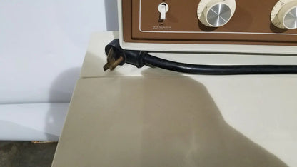 Black power cord with three-prong plug resting on the edge of beige beckman j2-21 refrigerated centriifuge appliance