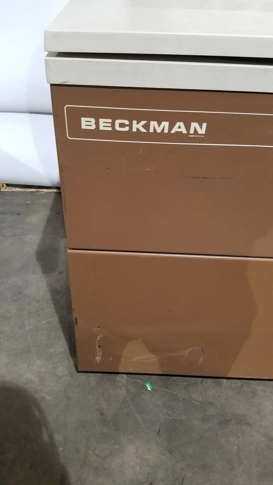 Brown beckman two-drawer filing cabinet with white top alongside beckman j2-21 refrigerated centrifuge unit