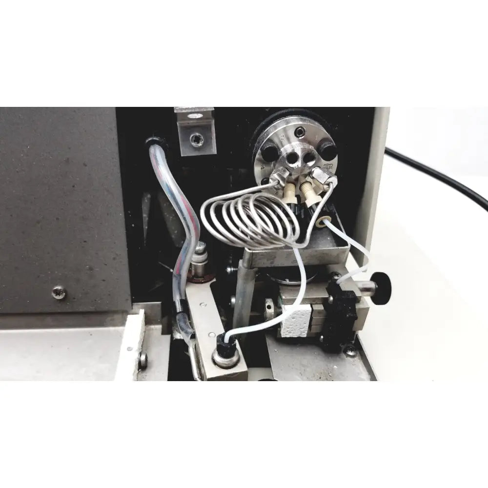 Metallic cylindrical component with threaded ports and coiled tubing in beckman system gold autosampler for hplc laboratory use