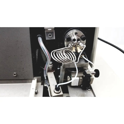 Metallic cylindrical component with threaded ports and coiled tubing in beckman system gold autosampler for hplc laboratory use