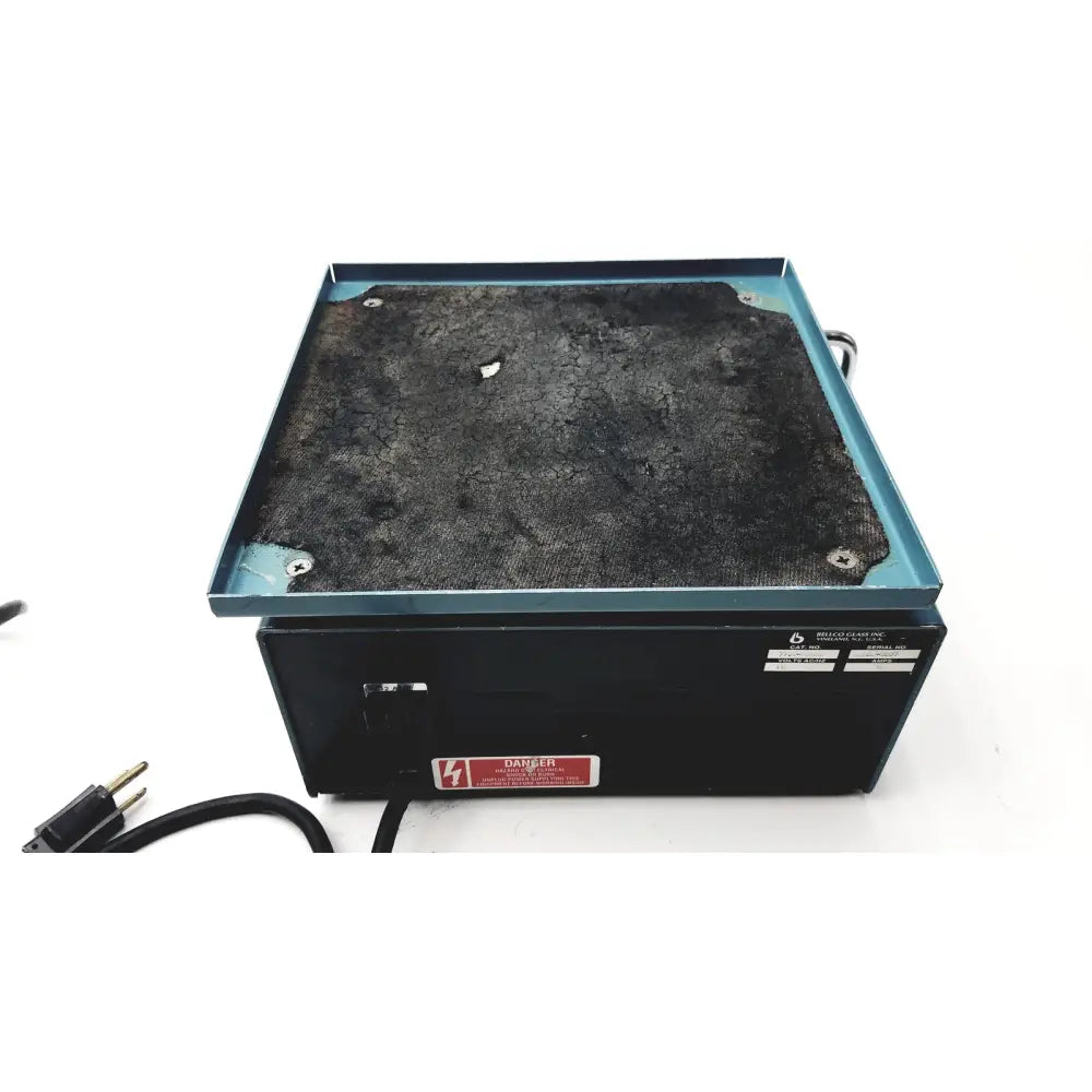 Black rectangular laboratory hot plate with cracked dark gray surface and teal metal frame on bellco orbital shaker 7744-02020