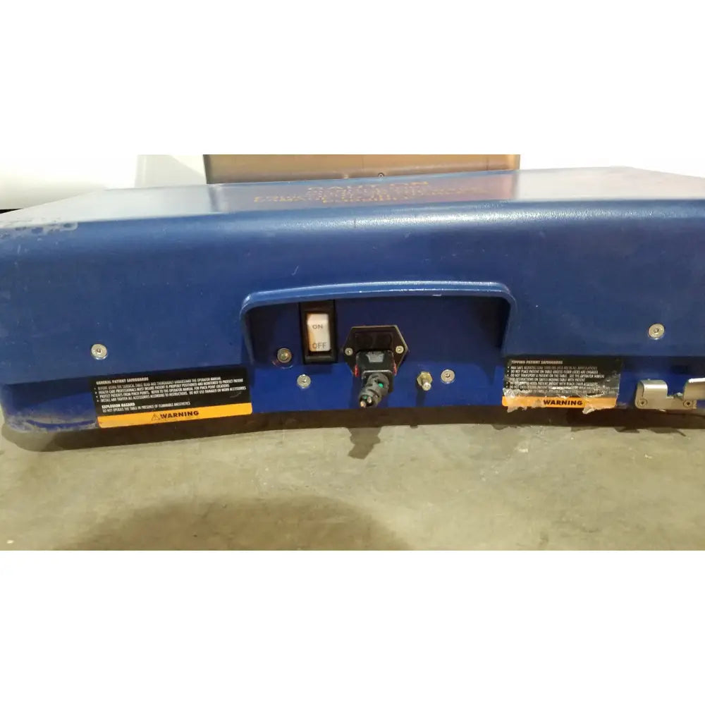 Blue industrial-grade power tool with black switch and connector port shown on the berchtold d850 operon surgical table