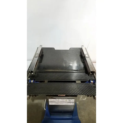 Black carbon fiber conveyor belt with metallic side rails and blue rollers on berchtold d850 operon surgical table
