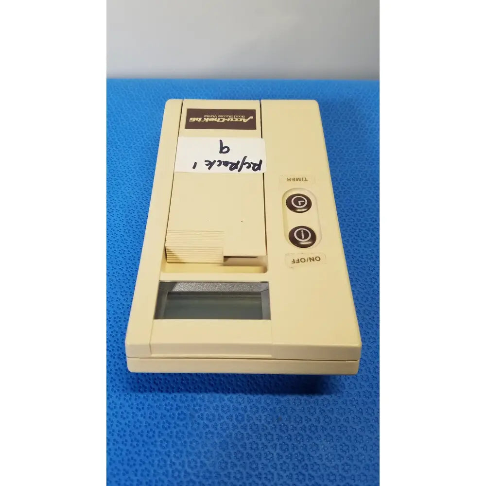 Cream-colored plastic vcr-105 pocket-sized video cassette recorder with timer buttons next to bio-dynamics accu-chek blood glucose monitor